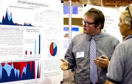  An undergraduate researcher presents his findings using a large-format poster at the Longhorn Research Bazaar